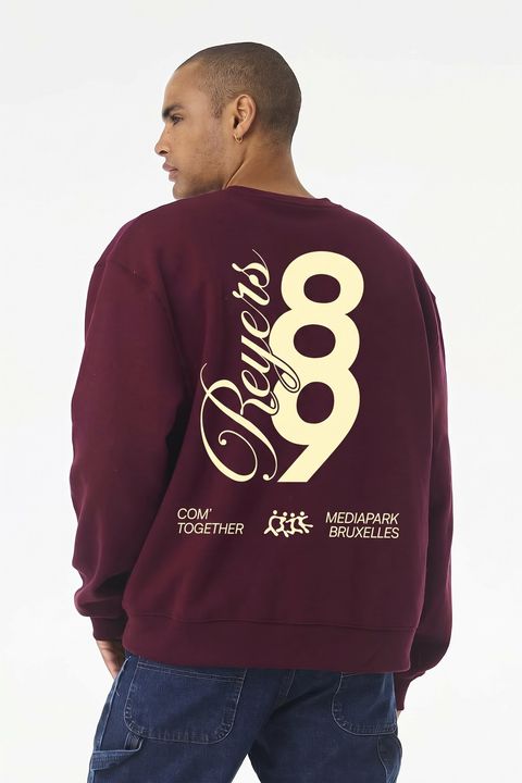 Une personne de dos porte le pull Reyers89, grand 89 et script Reyers imprimés en crème